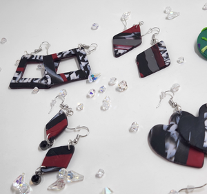 Various shapes of red, white, and black jewelry with clear crystals on a white background.